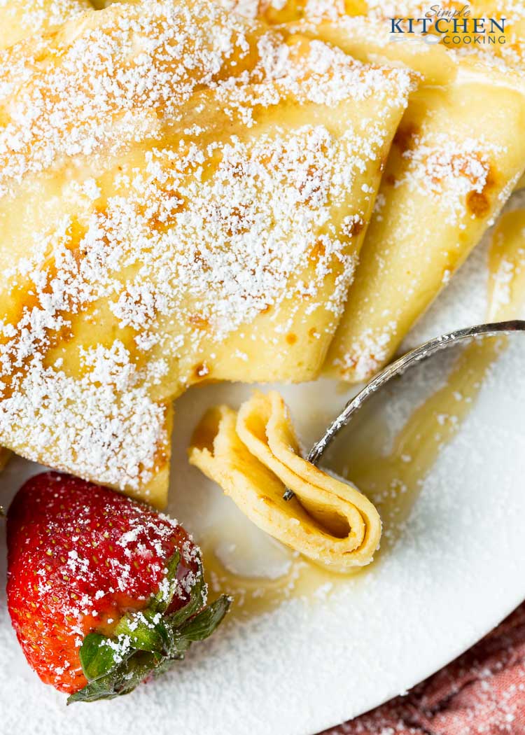 Fork with a piece of pancake on top with strawberries