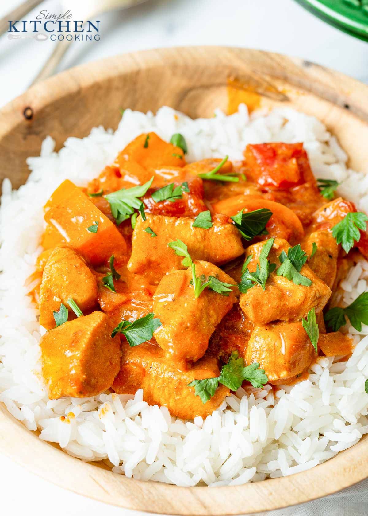 Chicken Paprikash over a bed of rice in wooden bowl